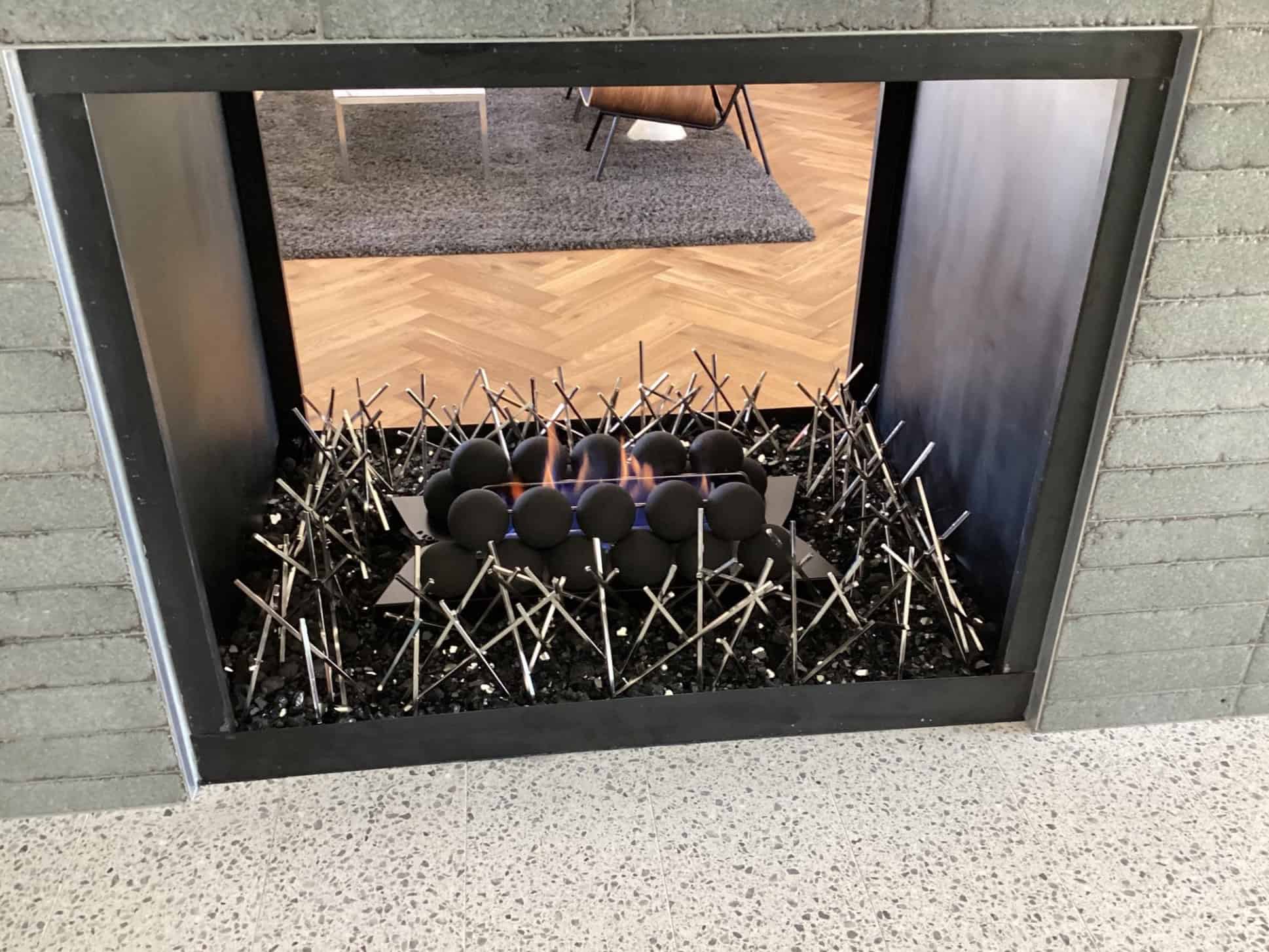 a custom gas fireplace with black fire glass, nickel plated spikes - fire art and black cannonballs custom built in Phoenix AZ by Magic Touch Mechanical