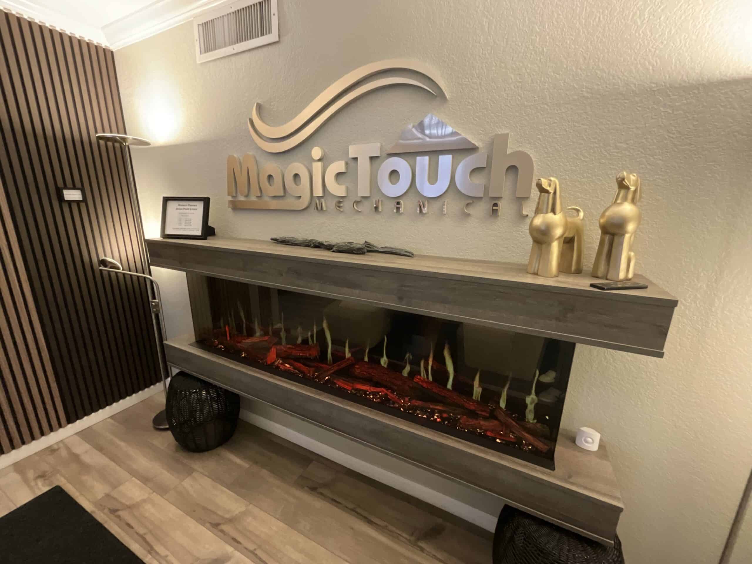 Reception area of Magic Touch Mechanical office with a wall mounted modern linear electric fireplace in driftwood gray wood mantel suite below a Magic Touch Mechanical sign on the wall in copper lettering